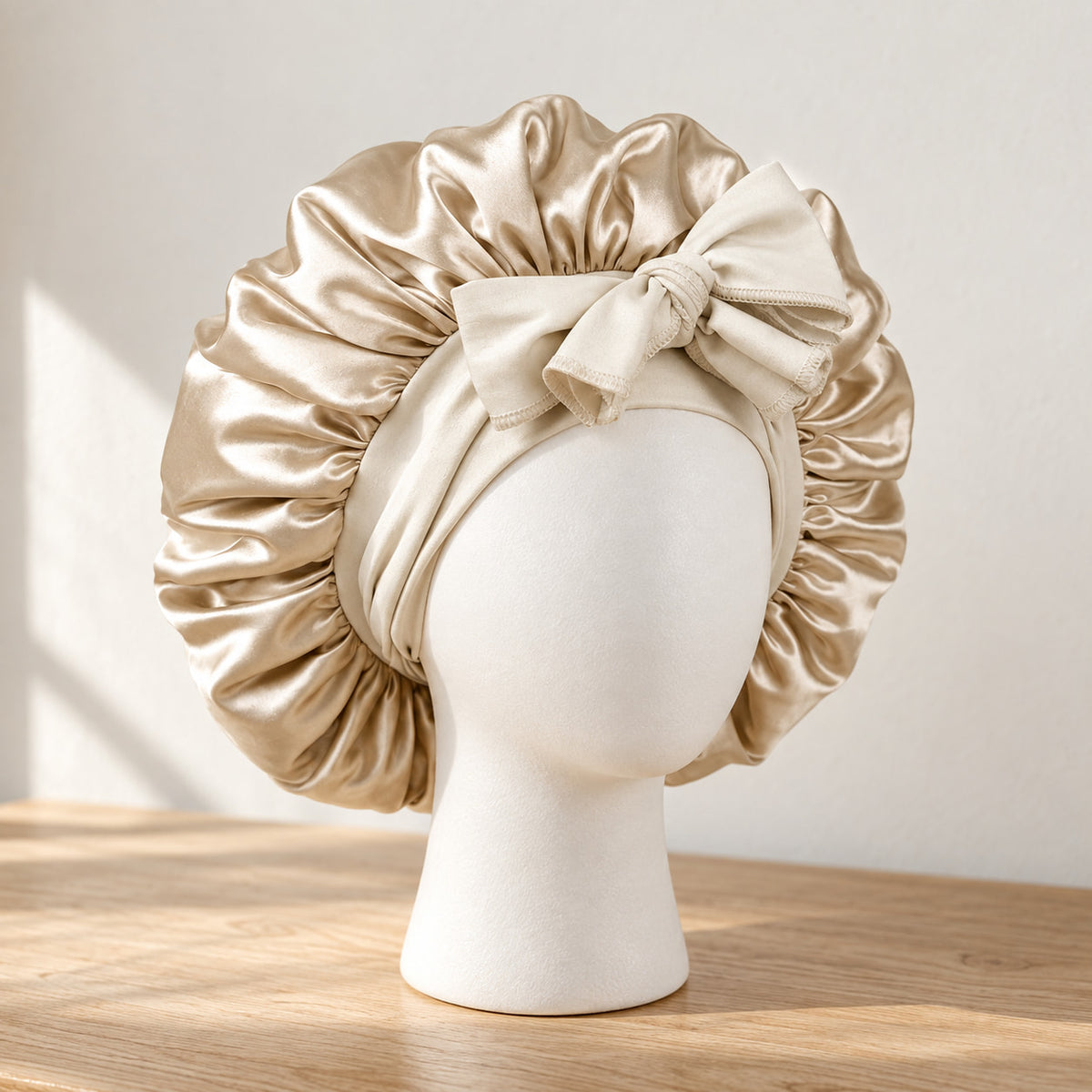 Bonnet de nuit en satin beige à nouer, présenté sur une tête de mannequin blanche
